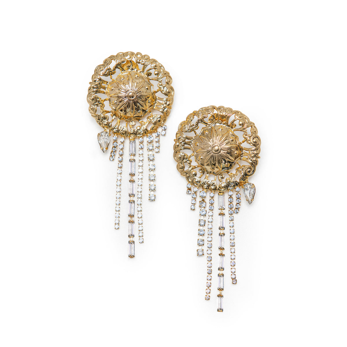 A pair of ornate gold-toned statement earrings with intricate filigree detailing and different sized dangling, clear Swarovski crystals, shown on a plain white background.