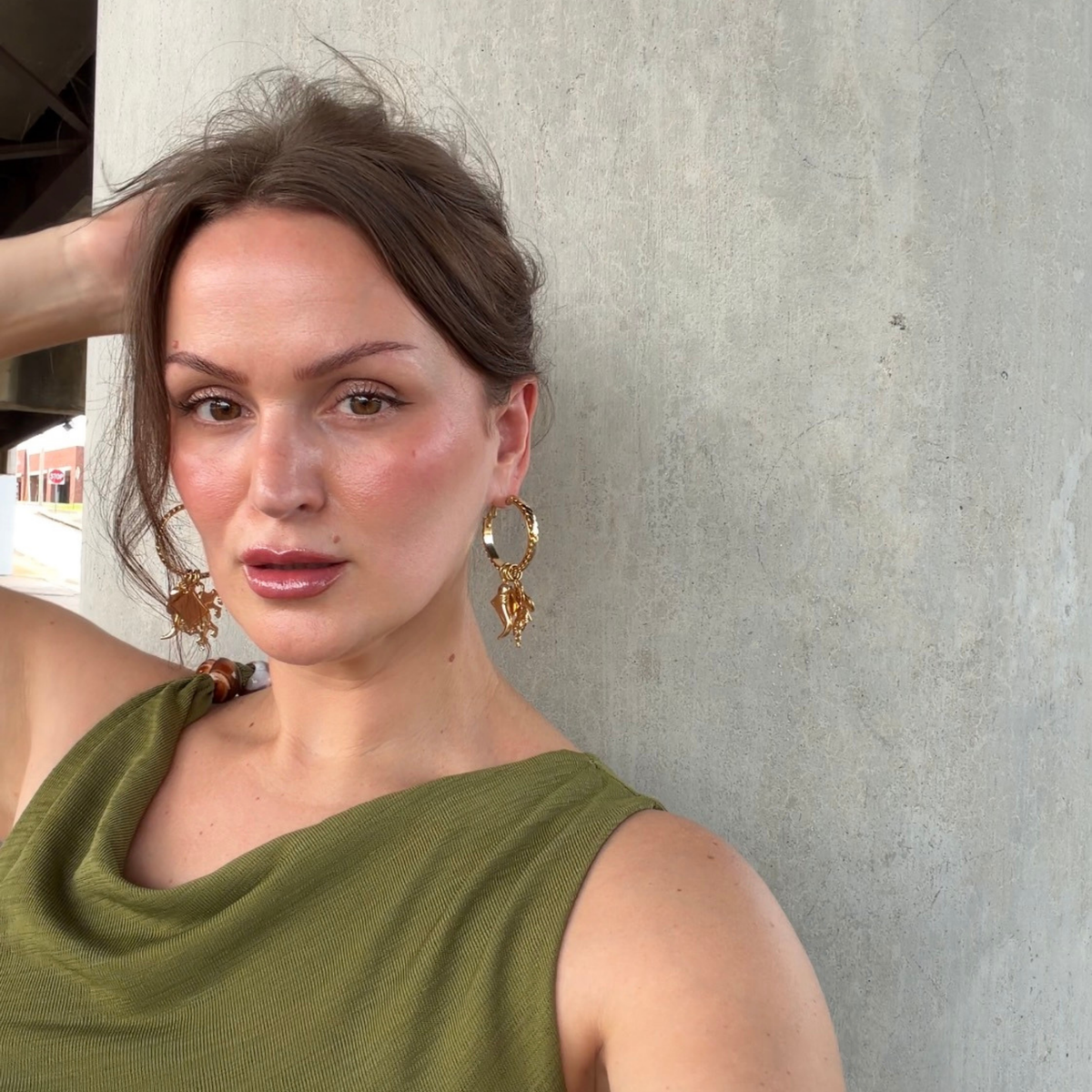 A woman wearing gold-toned hinge hoop earrings with vintage chain details with four removable charms: lion, diamond, chili pepper, and spade with clear Swarovski crystal accents.